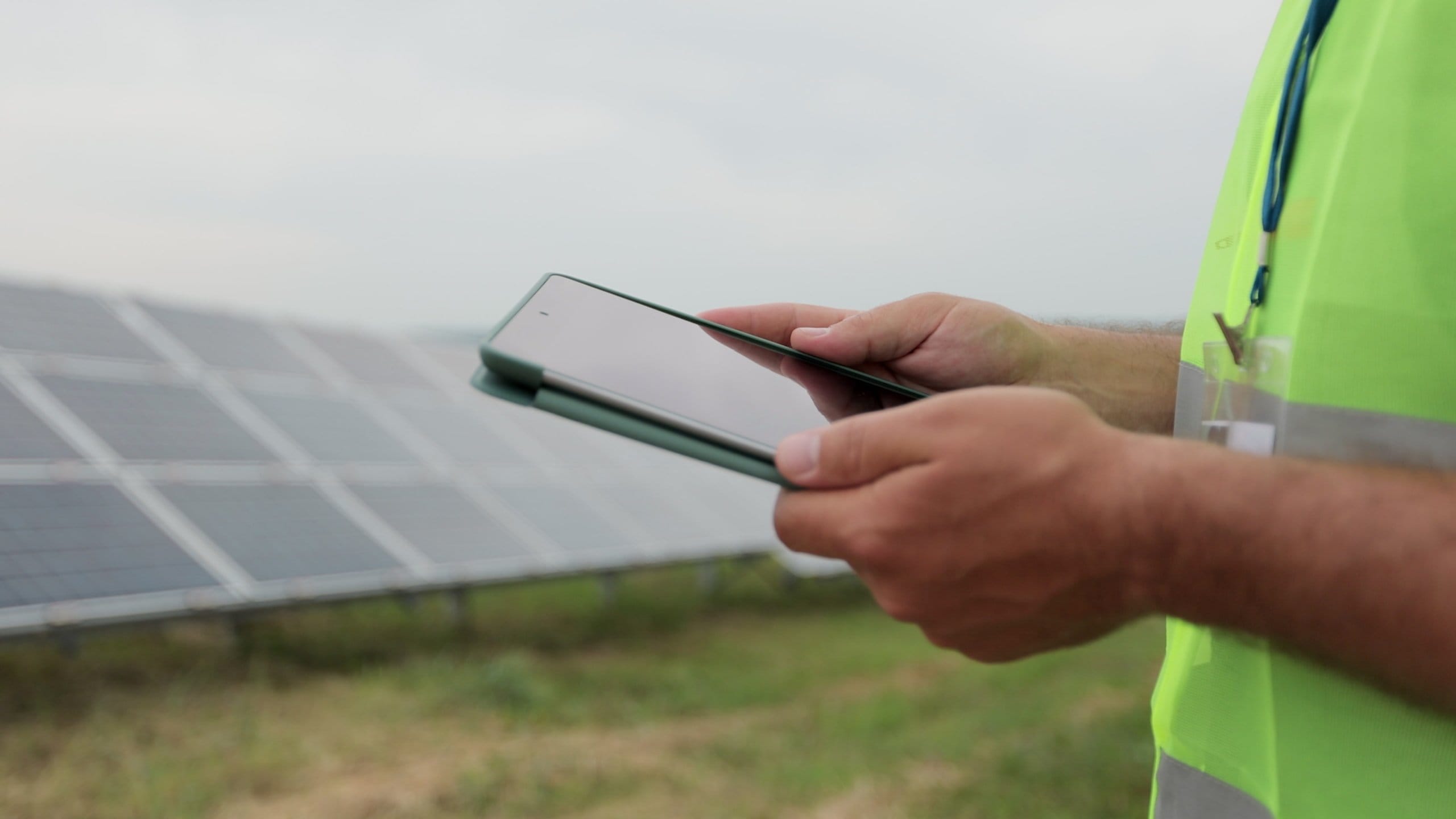 Close up of engineer is checking with tablet PC an operation of field of photovoltaic solar panels. Solar panel field. Clean energy production. Green energy.